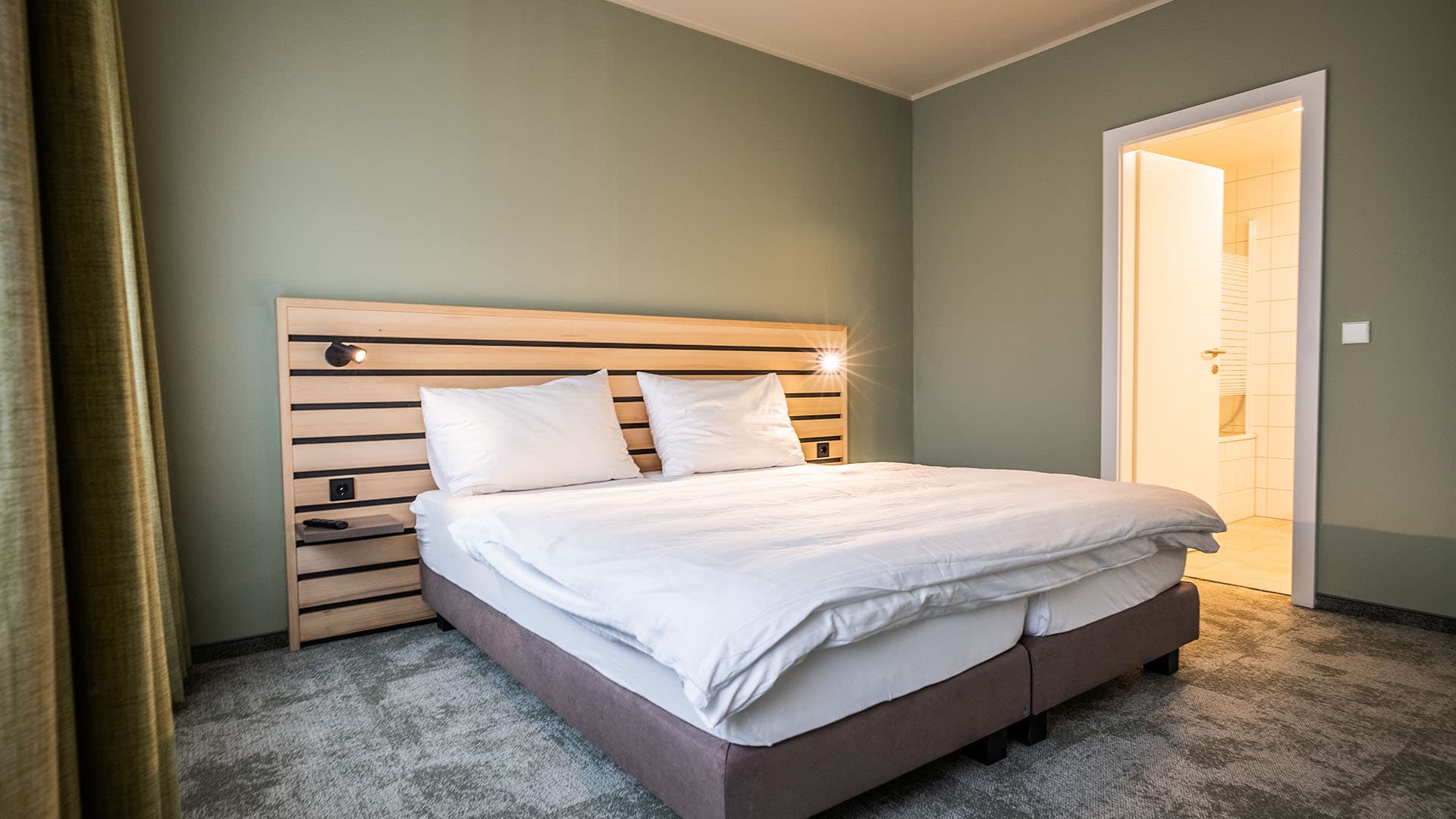 A modern motel room in the Flexy Motel Spielberg with a double bed and an adjoining bathroom.