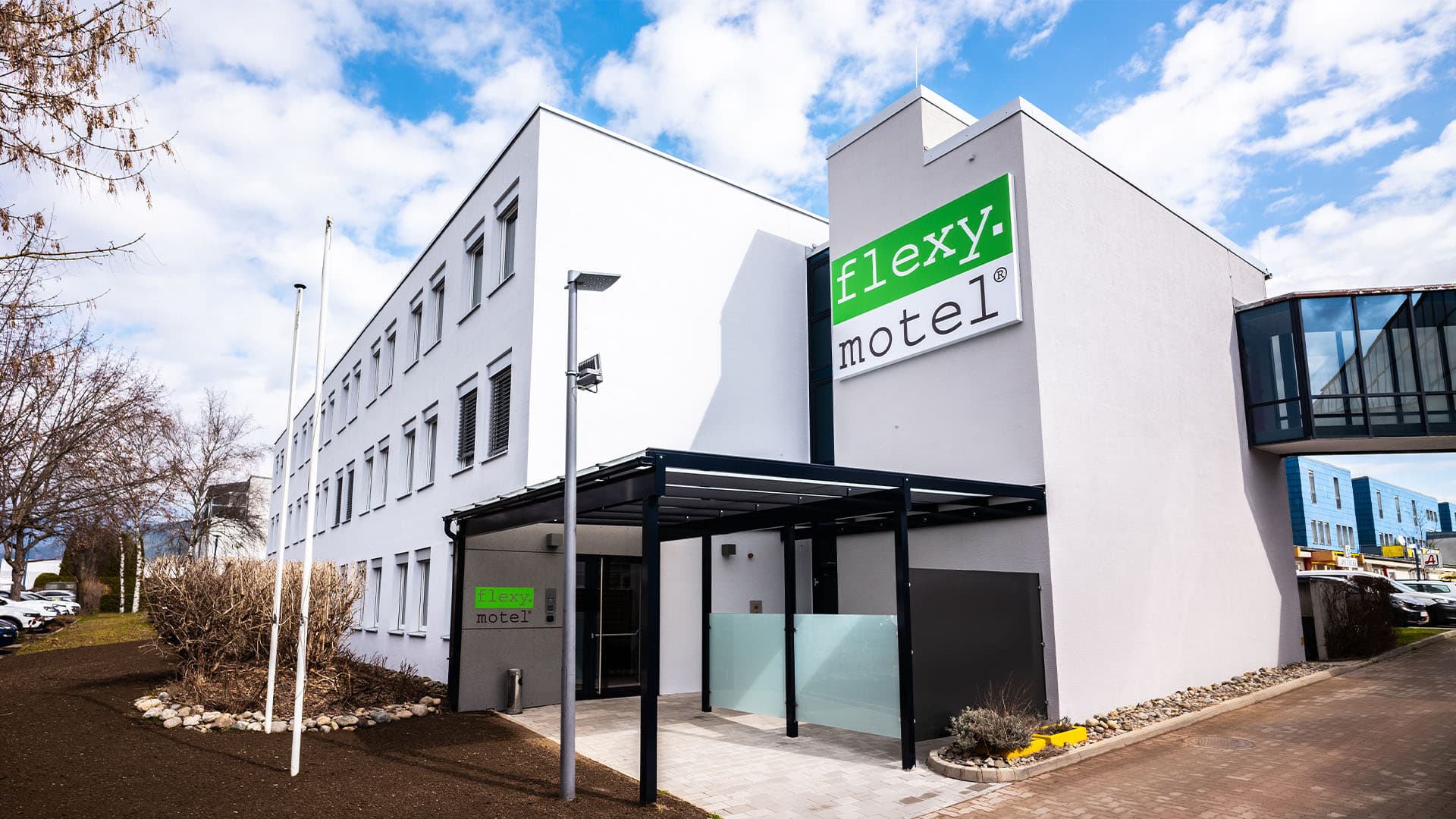 Exterior view of the Flexy Motel in Spielberg with a modern building and glass roof at the entrance.