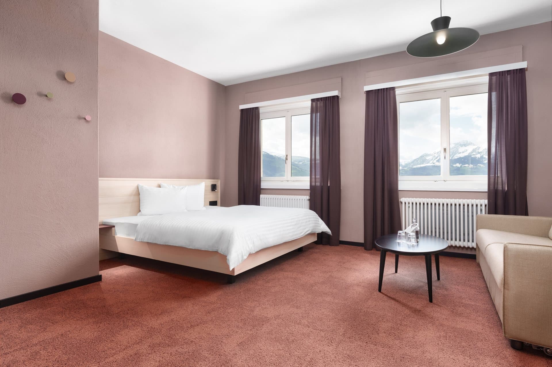 Bright hotel room in the b smart monastery with double bed window with mountain view sofa and coffee table on carpet.