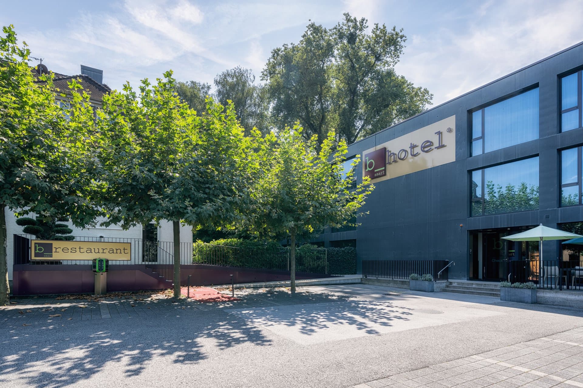 Außenansicht des bsmart Hotel Widnau mit angrenzendem restaurant bei sonnigem Wetter.