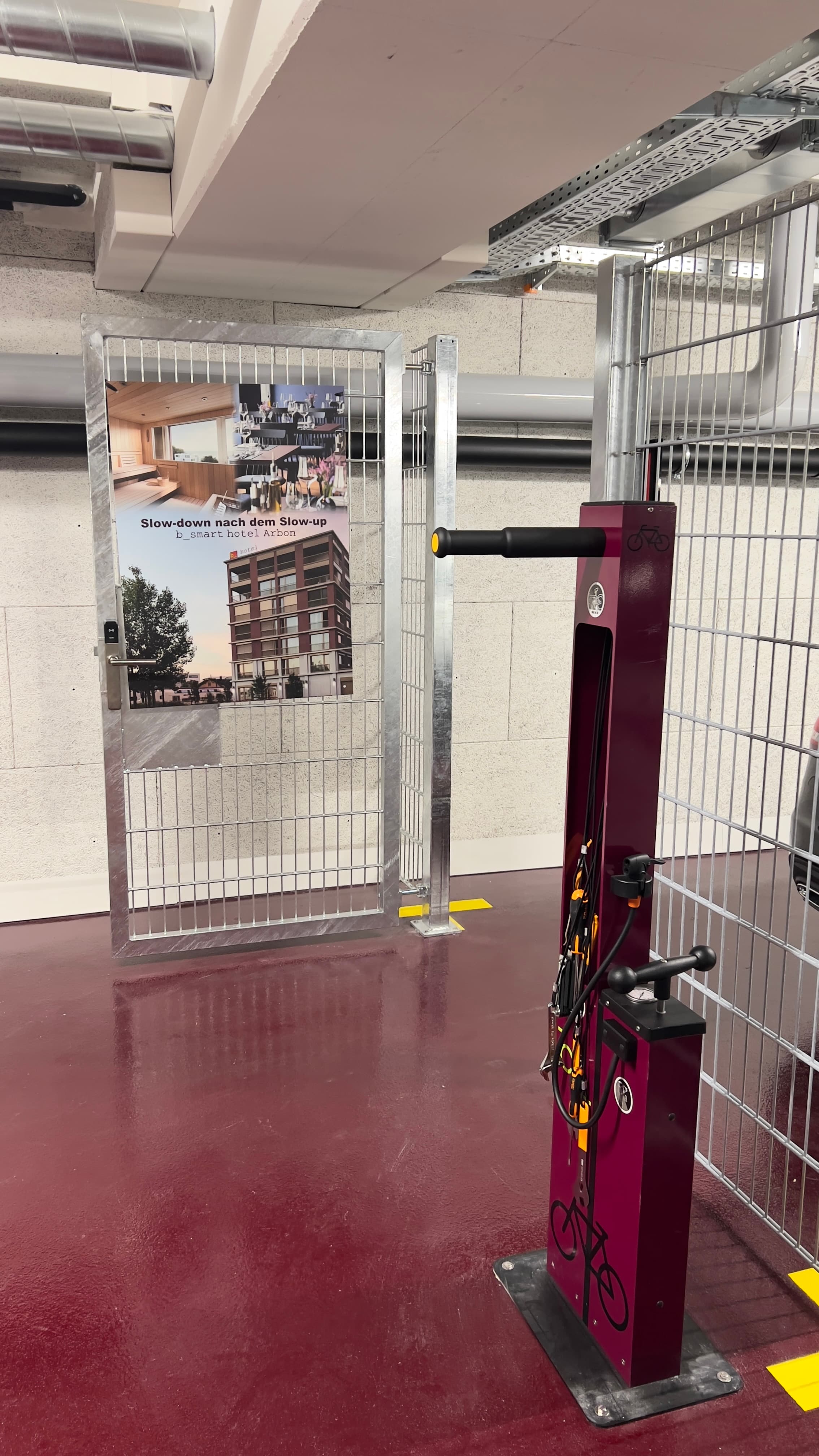 A bike cellar in Arbon with a purple repair stand and a sign advertising the b_smart hotel Arbon