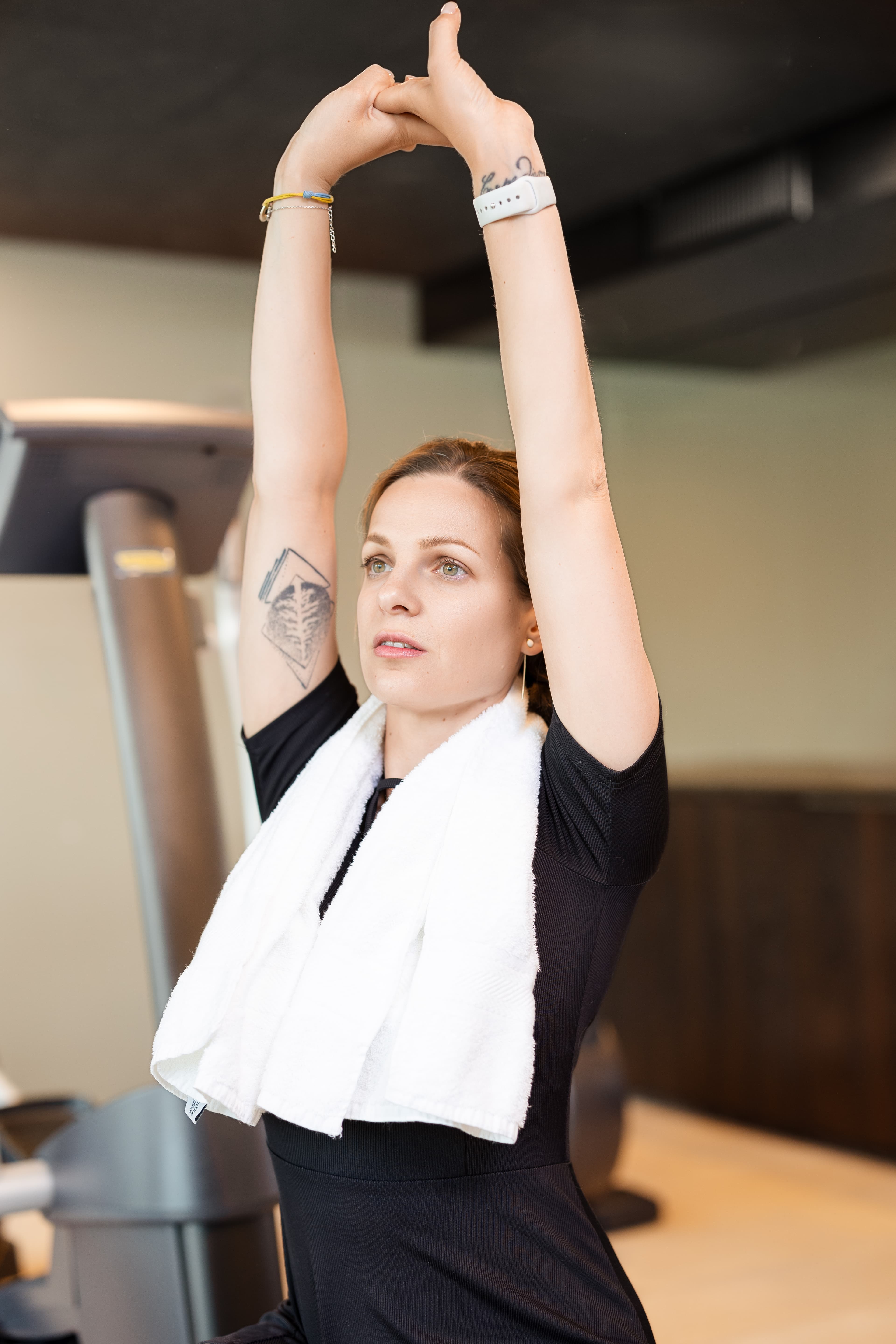 Woman doing stretching exercises in the fitness area of the BSmart Hotel in Widnau with a towel around her neck.