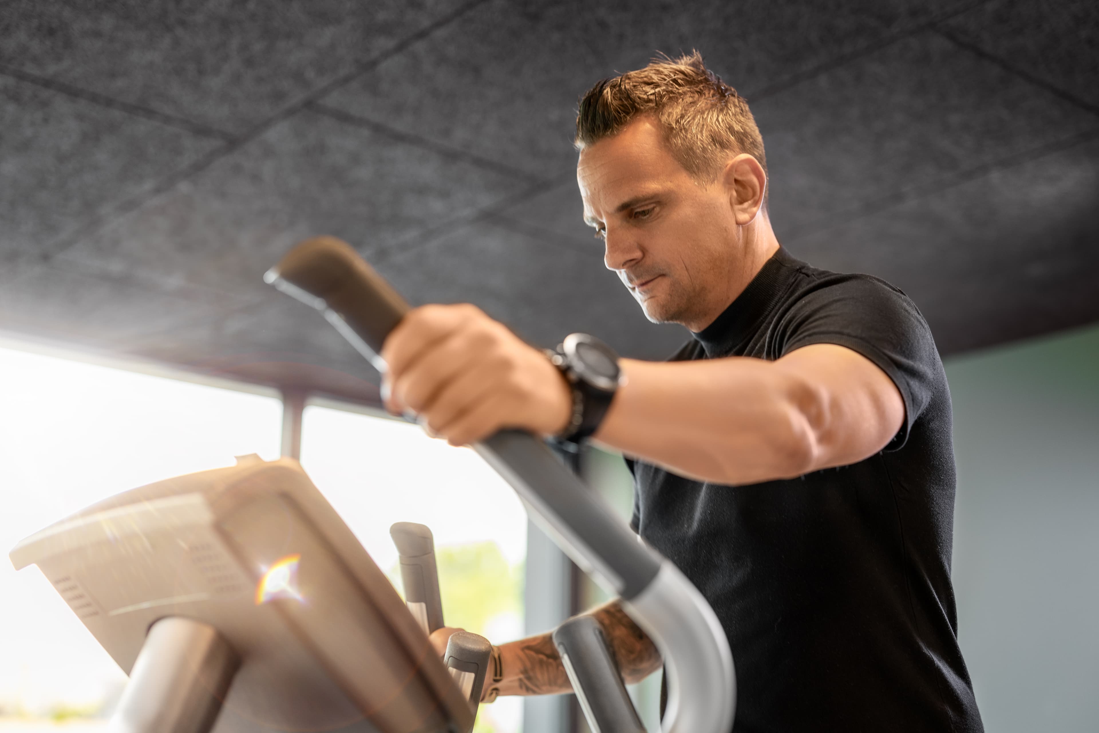 A man is working out on an elliptical trainer in the fitness area of the B smart Hotel Widnau.