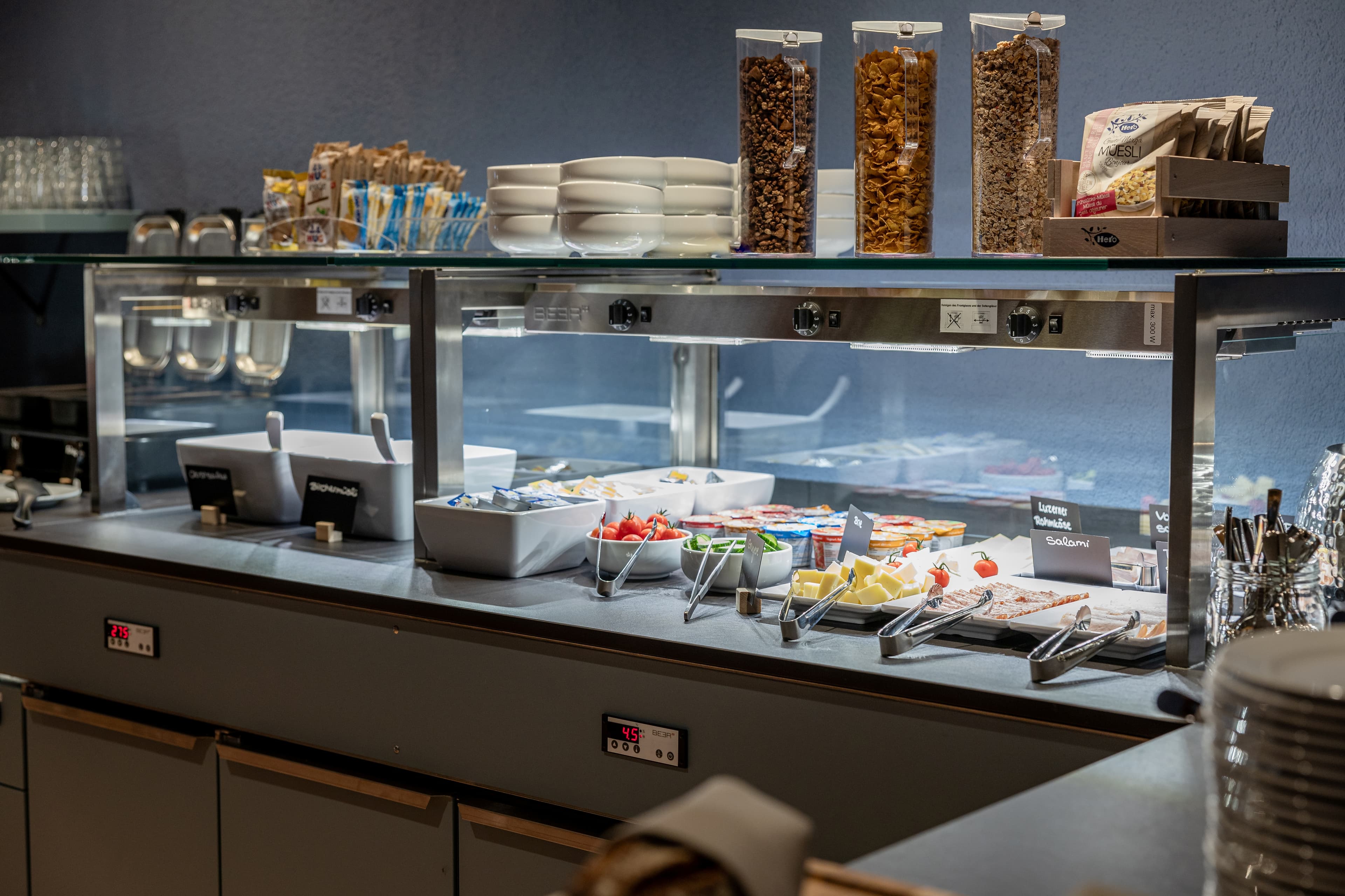 Breakfast buffet at b_smart hotel Arbon with various cereals, cold cuts, cheese, fruit, and yogurt