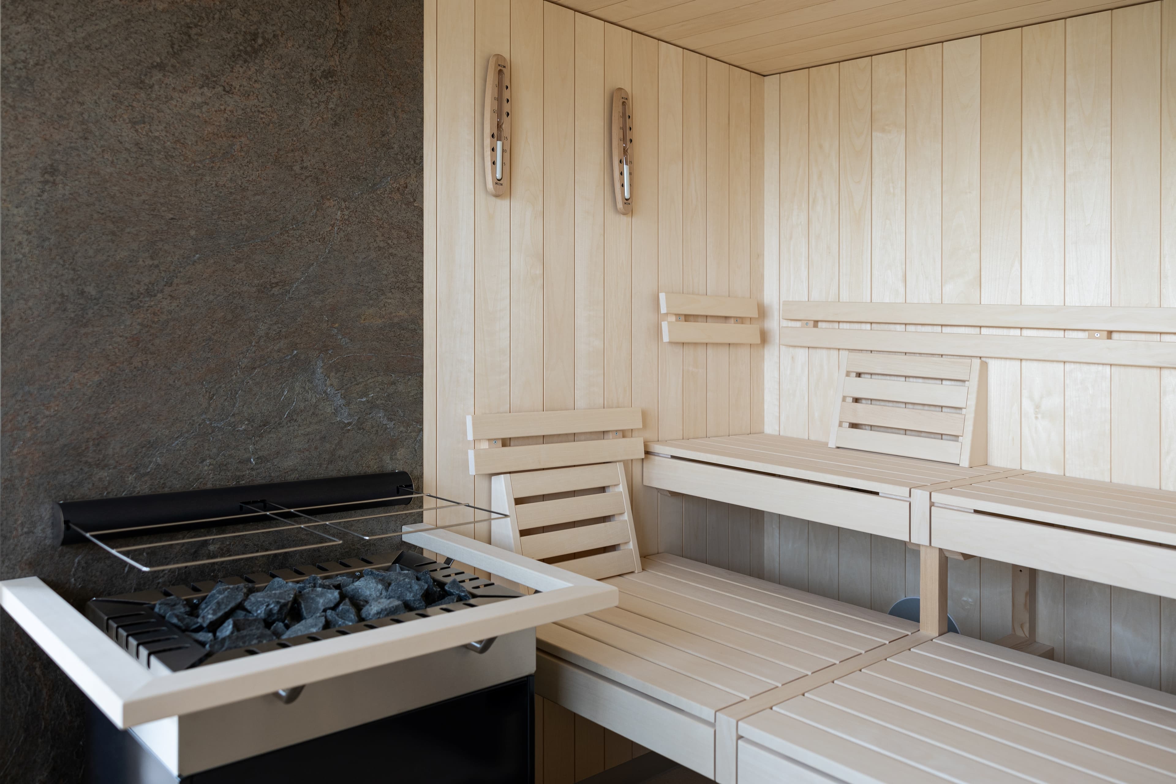 Sauna made of light wood with a stone grill in the B_smart Hotel Arbon