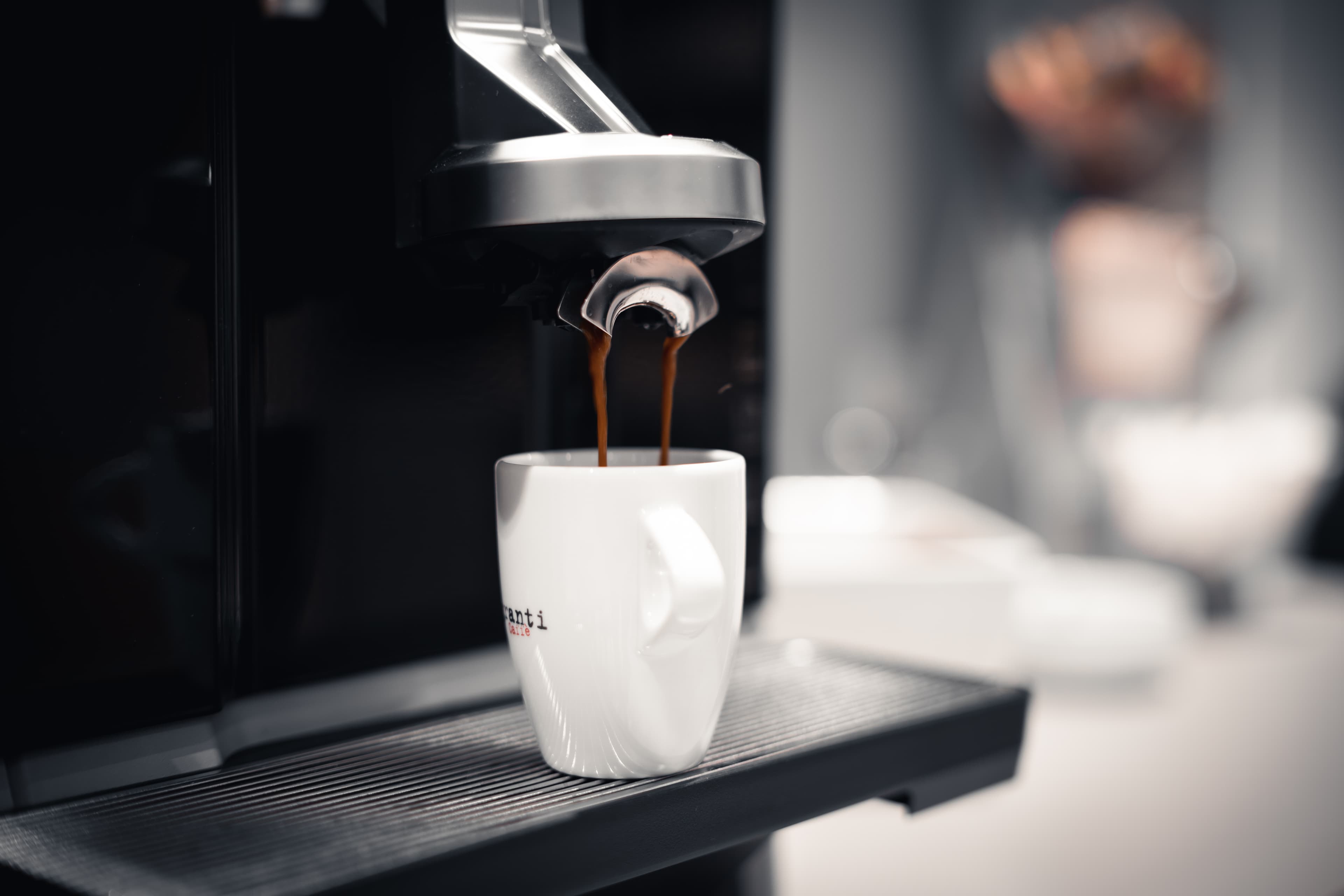 A coffee maker pours fresh coffee into a white cup at the b_smart motel Basel.