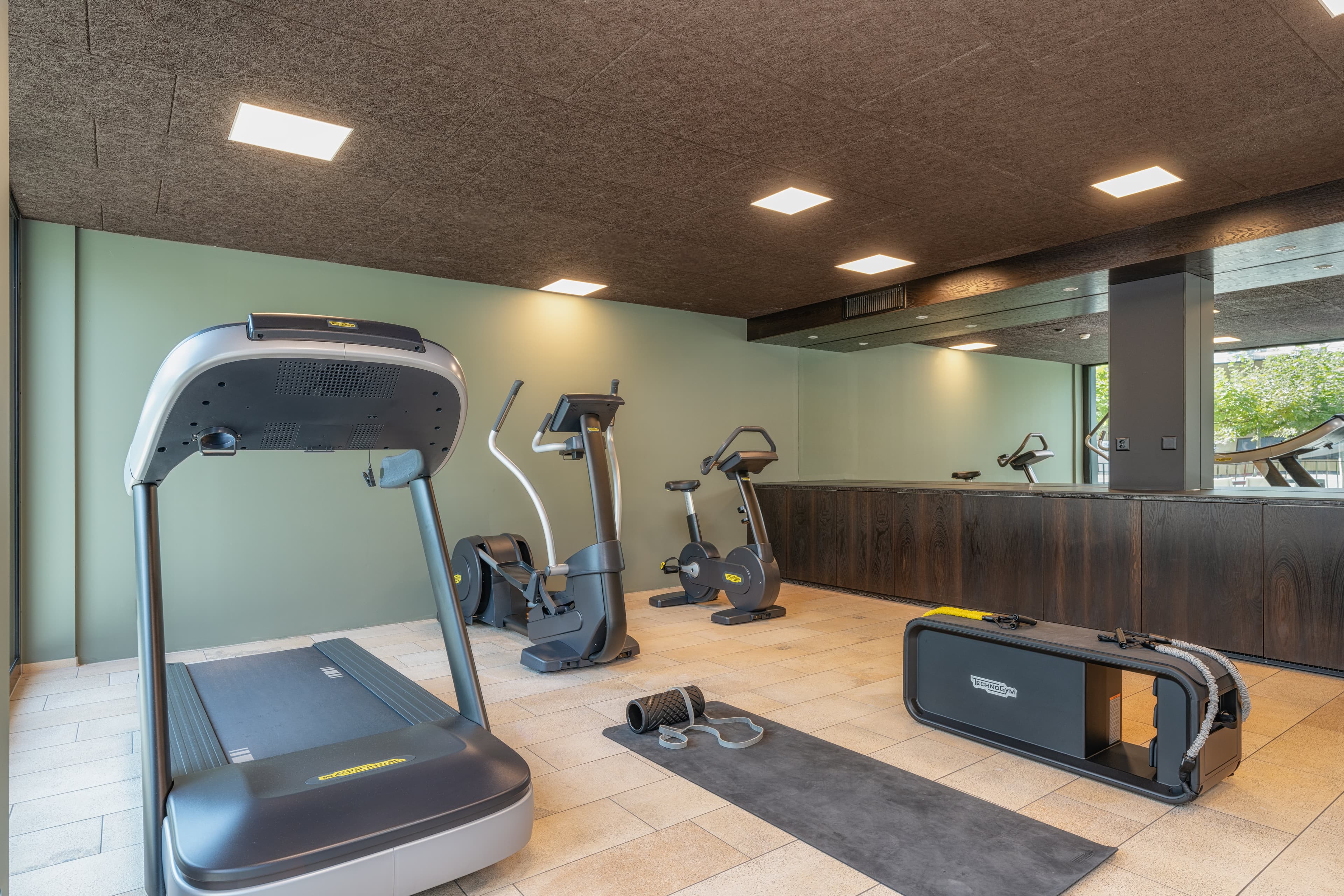 Fitness room at the b smart Hotel Widnau with treadmill, exercise bike, cross trainer, and fitness mat.