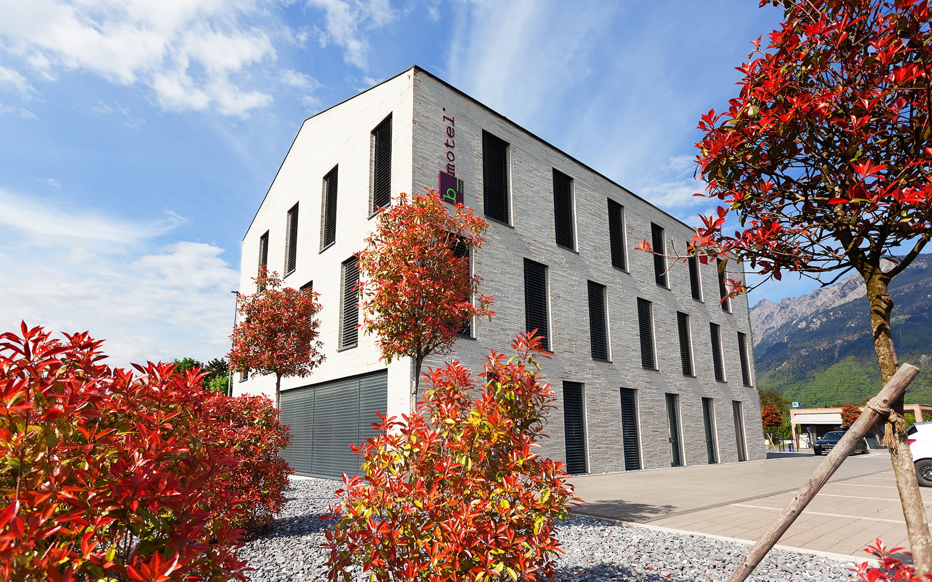 A modern building of the b smart motel in Sevelen with clear lines and red plants in the foreground