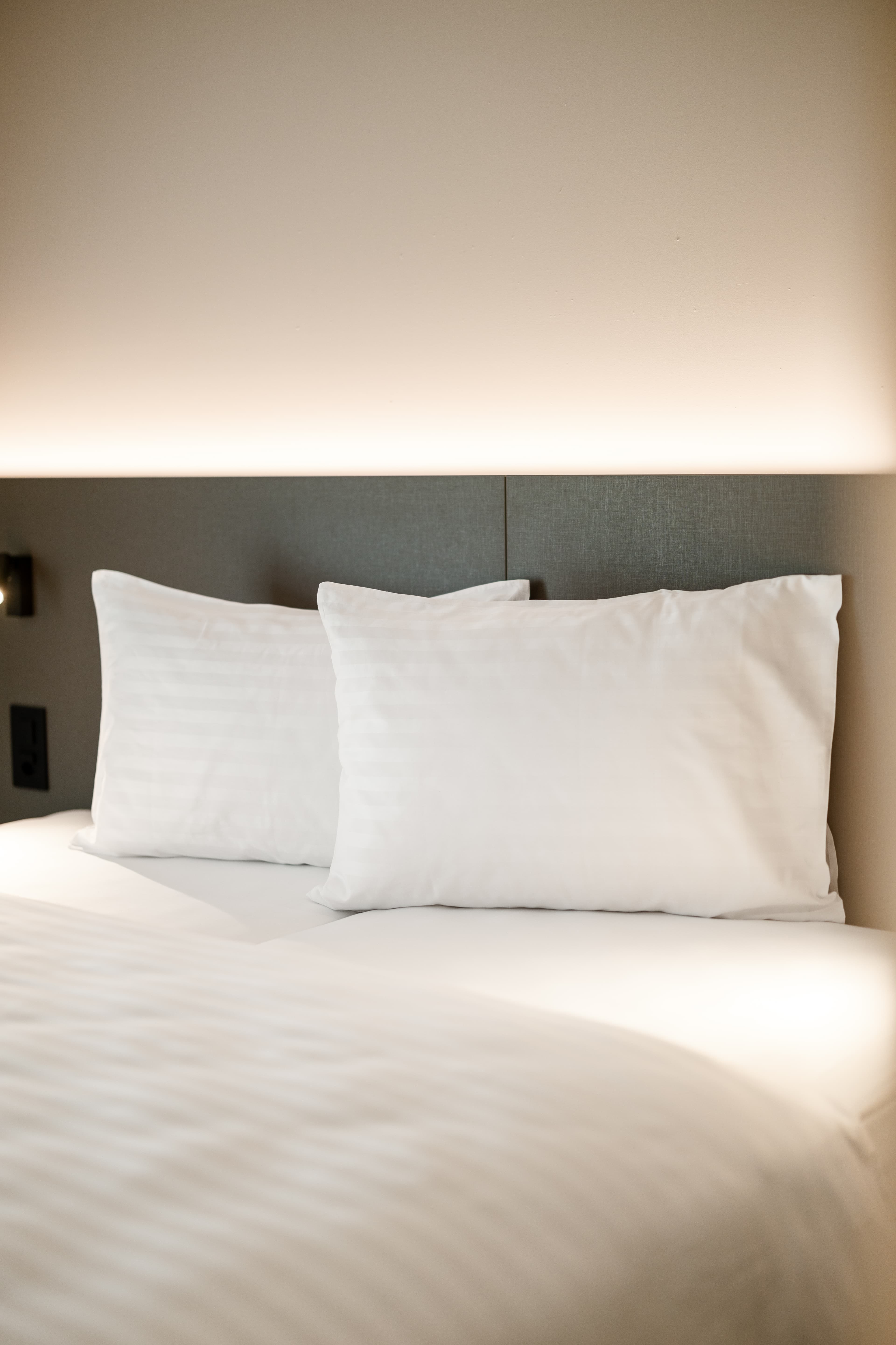 A double room at the B Smart Motel Amriswil with a large well-lit bed with two white pillows.