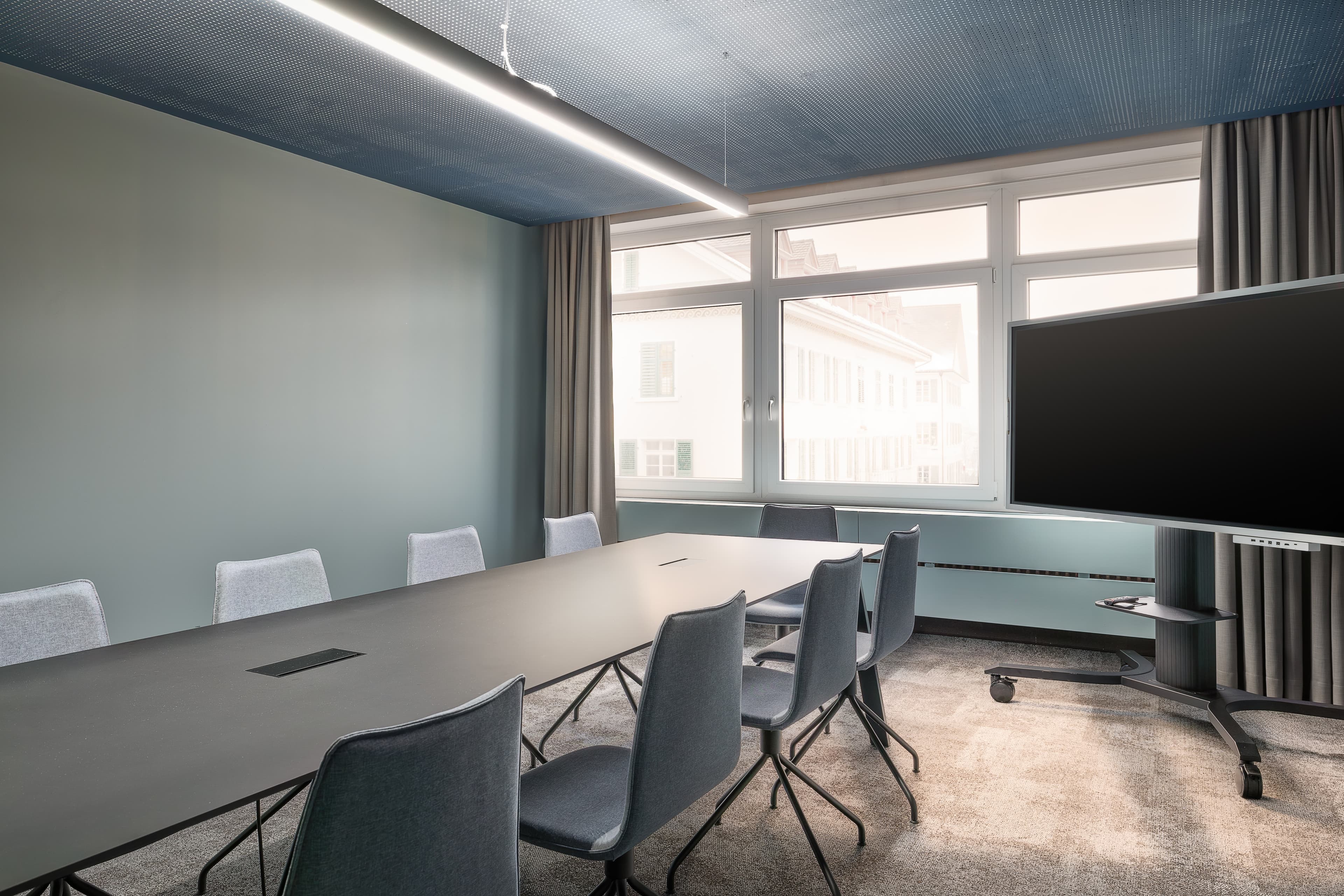 Modern meeting room in the B Smart Hotel Schonenwerd in Gretzenbach with a rectangular table several gray chairs and a large screen