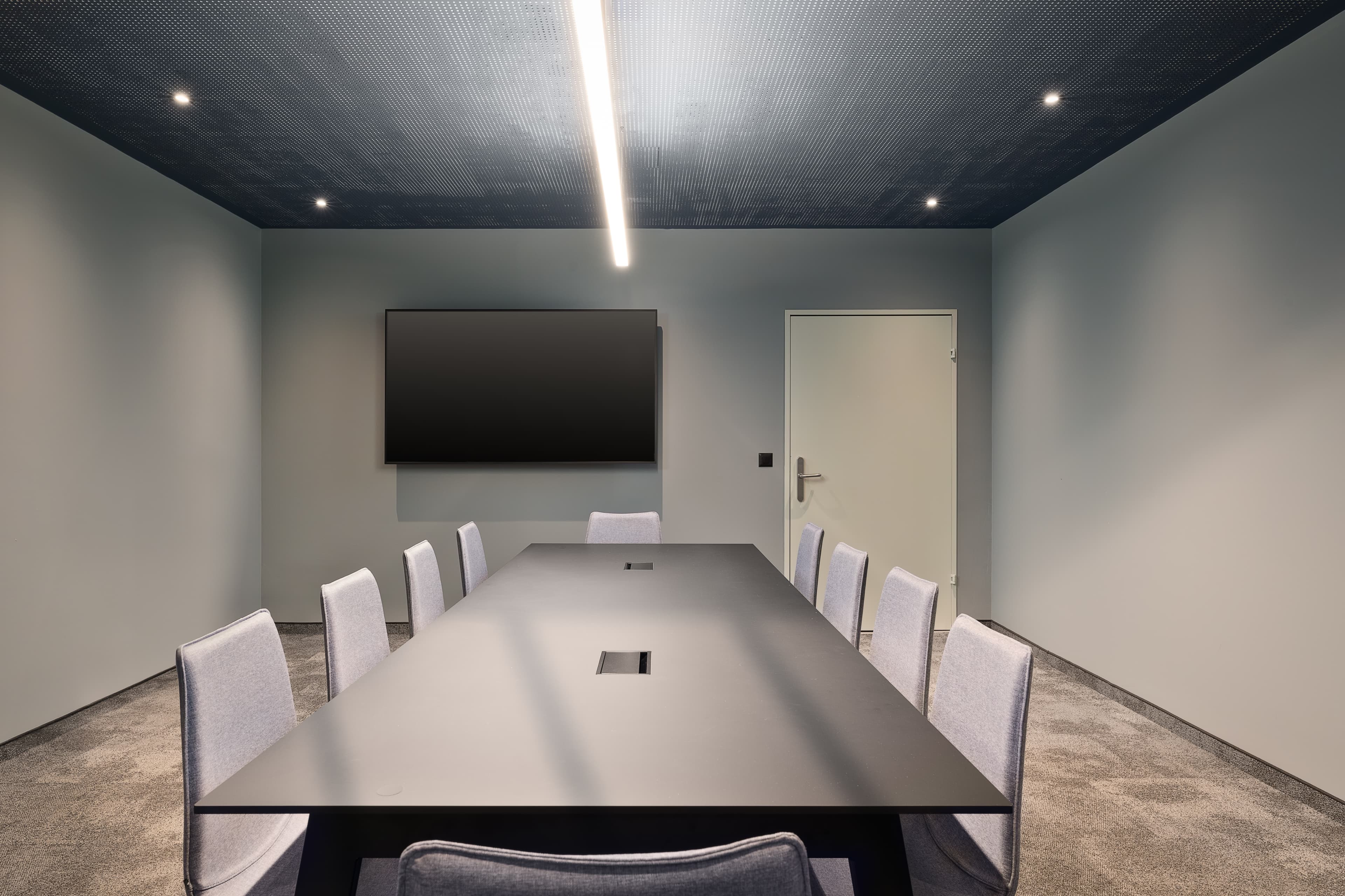 Modern meeting room in the B smart Hotel Schonenwerd with a long table gray chairs flat-screen television and minimalist decor