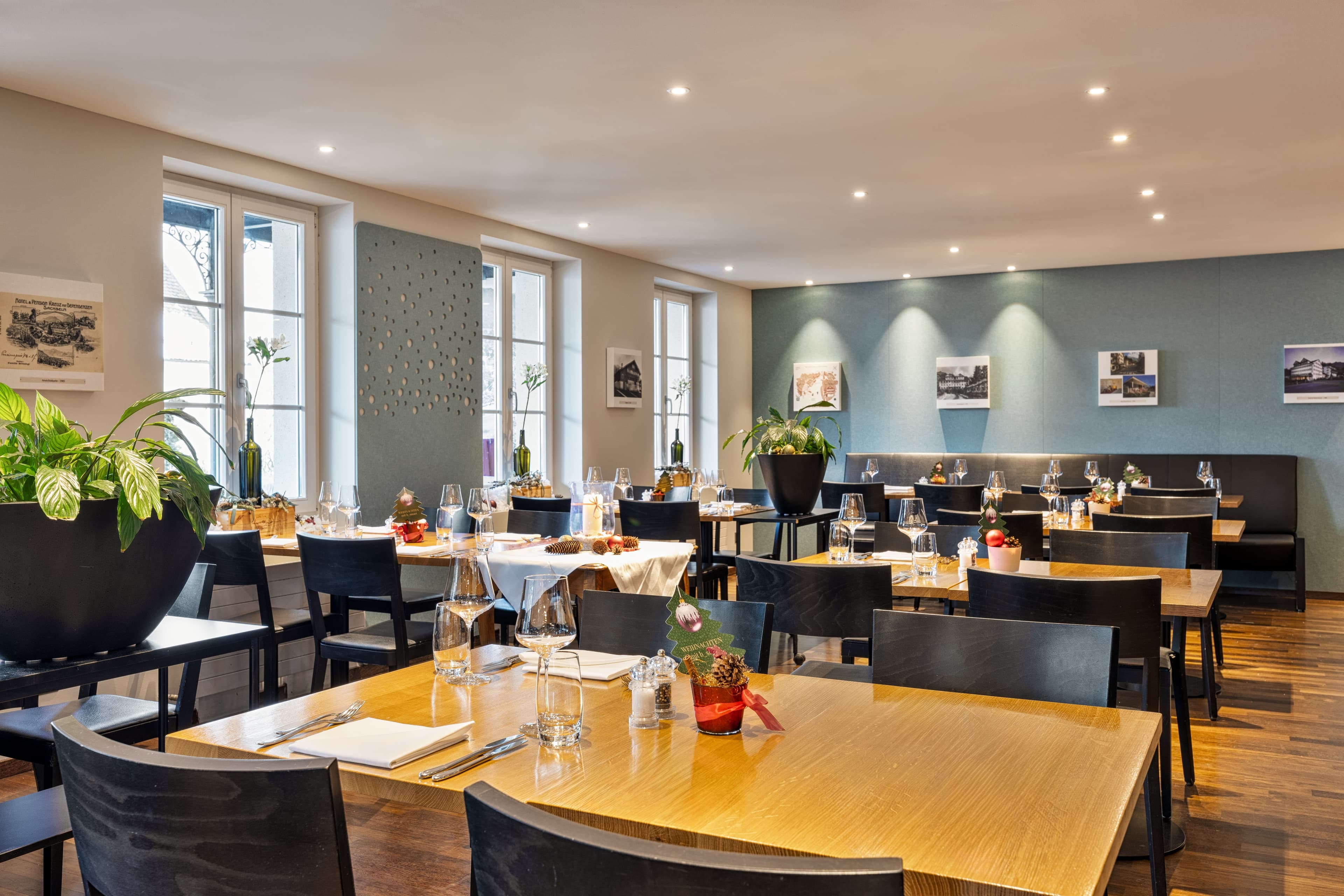 A stylishly furnished restaurant in the Hotel Kreuz with set tables, modern wooden furniture, and decorative plants.