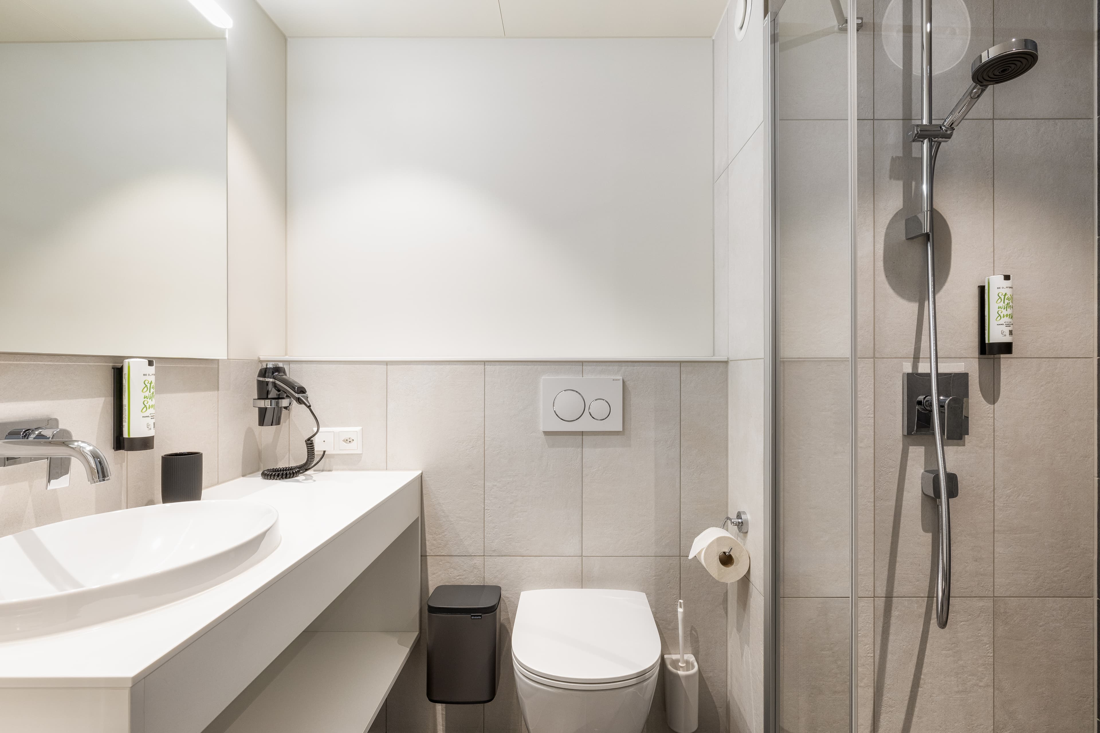 A modern bathroom at the B Smart Motel Amriswil with a sink, toilet, and shower.