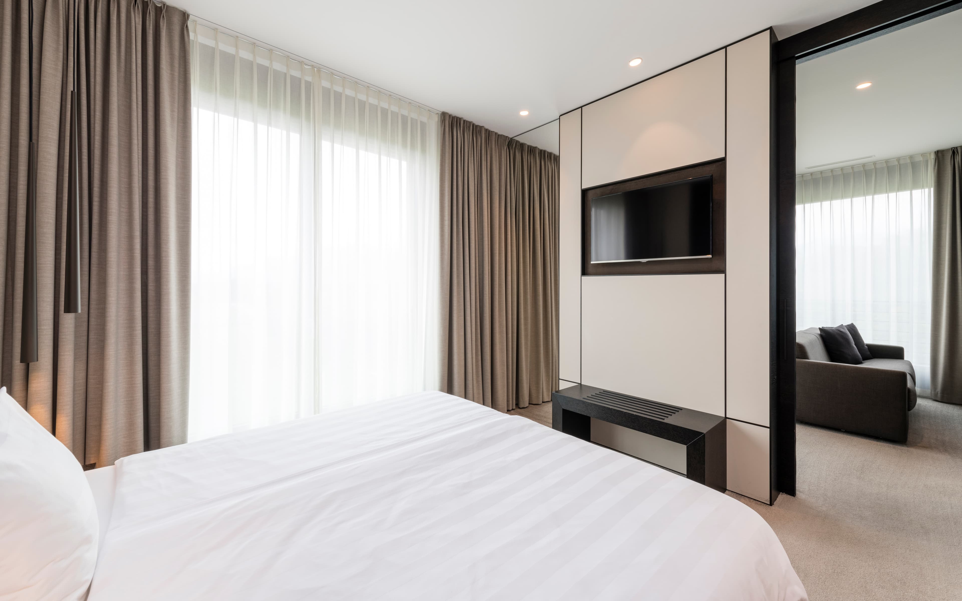 A modern hotel room in the B_smart Hotel in Bendern with a comfortable bed, a flat screen TV, and an adjacent seating area.